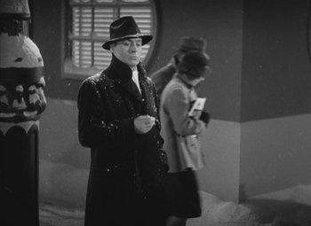 Movie still from “Love Affair” (1939), directed by Leo McCarey – A man in a hat and a coat standing next to a woman in a hat; Medium shot, Low angle