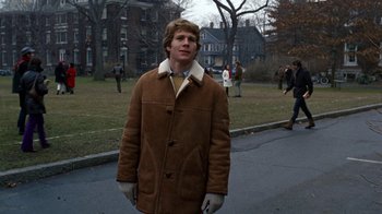 Movie still from “Love Story” (1970), directed by Arthur Hiller – A man in a brown coat standing on the side of a road; Medium shot, Over the shoulder angle
