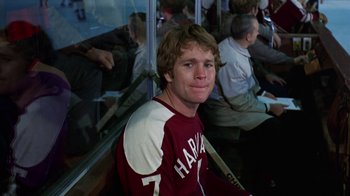 Movie still from “Love Story” (1970), directed by Arthur Hiller – A man sitting on a bench in front of a crowd; Medium shot, High angle