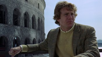 Movie still from “Love Story” (1970), directed by Arthur Hiller – A man in a jacket and sweater leaning against a wall; Close Up shot, Low angle