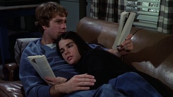 Movie still from “Love Story” (1970), directed by Arthur Hiller – A man and a woman laying on a couch reading books; Medium shot, High angle