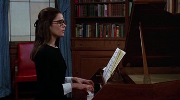 Movie still from “Love Story” (1970), directed by Arthur Hiller – A woman playing the piano in front of a bookshelf; Medium shot, Over the shoulder angle