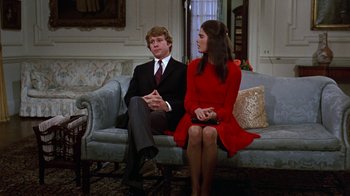 Movie still from “Love Story” (1970), directed by Arthur Hiller – A man and a woman sitting on a couch in a living room; Medium shot, Low angle