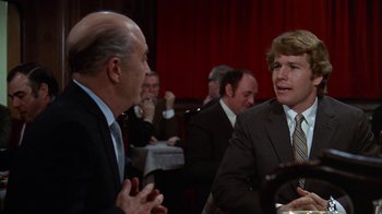 Movie still from “Love Story” (1970), directed by Arthur Hiller – Two men in business suits talking to each other; Medium shot, Over the shoulder angle