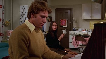Movie still from “Love Story” (1970), directed by Arthur Hiller – A man and a woman are sitting in a kitchen; Medium shot, Low angle