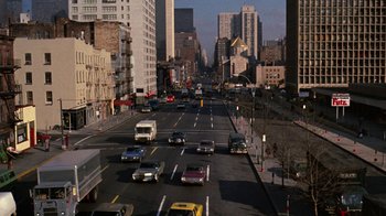 Movie still from “Love Story” (1970), directed by Arthur Hiller – A city street filled with lots of traffic and tall buildings; Extreme Wide shot, High angle