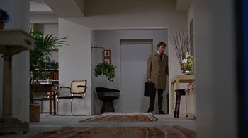 Movie still from “Love Story” (1970), directed by Arthur Hiller – A man holding a briefcase standing in a room; Wide shot, Low angle