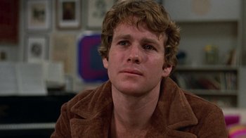 Movie still from “Love Story” (1970), directed by Arthur Hiller – A young man in a brown jacket looking to his left; Close Up shot, Low angle