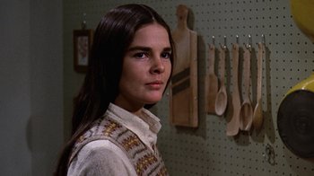 Movie still from “Love Story” (1970), directed by Arthur Hiller – A woman standing next to a wall of wooden spoons; Close Up shot, Low angle