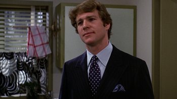 Movie still from “Love Story” (1970), directed by Arthur Hiller – A man in a suit and tie standing in front of a mirror; Close Up shot, Low angle