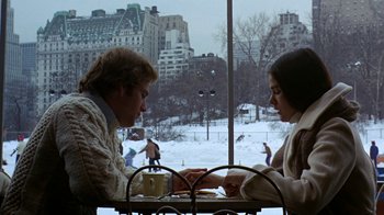 Movie still from “Love Story” (1970), directed by Arthur Hiller – A man and a woman sitting at a table in front of a window; Medium shot, Over the shoulder angle
