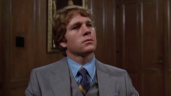 Movie still from “Love Story” (1970), directed by Arthur Hiller – A man wearing a suit and tie in a room; Close Up shot, Low angle