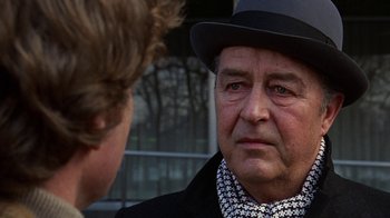 Movie still from “Love Story” (1970), directed by Arthur Hiller – An older man wearing a black hat and a black jacket; Close Up shot, Over the shoulder angle