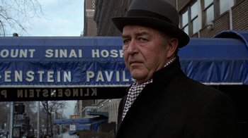 Movie still from “Love Story” (1970), directed by Arthur Hiller – An older man wearing a hat standing in front of a building; Close Up shot, Low angle