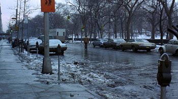 Movie still from “Love Story” (1970), directed by Arthur Hiller – A man walking down a street next to parked cars; Wide shot, High angle
