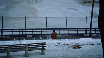 Movie still from “Love Story” (1970), directed by Arthur Hiller – A person sitting on a bench in the snow; Wide shot, High angle