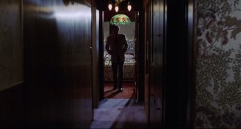 Movie still from “Love Streams” (1984), directed by John Cassavetes – A man standing in a hallway with a stained glass window in the background; Wide shot, Low angle