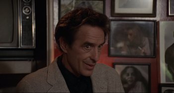Movie still from “Love Streams” (1984), directed by John Cassavetes – A person wearing a suit and smiling; Close Up shot, Over the shoulder angle