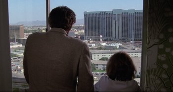 Movie still from “Love Streams” (1984), directed by John Cassavetes – A man and a woman looking out of a window at a city skyline; Wide shot, Over the shoulder angle