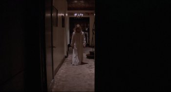 Movie still from “Love Streams” (1984), directed by John Cassavetes – A woman in a white robe walking down a hall way; Wide shot, High angle