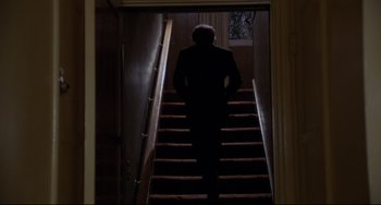 Movie still from “Love Streams” (1984), directed by John Cassavetes – A man in a suit walking down a set of stairs; Wide shot, Low angle