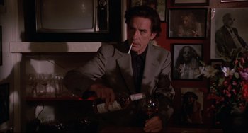 Movie still from “Love Streams” (1984), directed by John Cassavetes – A man in a suit is holding a bottle of wine and smoking a cigarette; Medium shot, Low angle