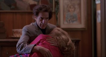 Movie still from “Love Streams” (1984), directed by John Cassavetes – A man holding a woman in his arms in front of a painting; Medium shot, Low angle
