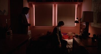 Movie still from “Love Streams” (1984), directed by John Cassavetes – Two people are sitting on a bed in a dark room; Wide shot, Over the shoulder angle