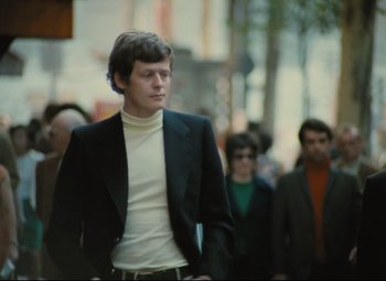 A man in a black jacket is walking down the street