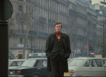A man standing on the side of the road in front of some cars