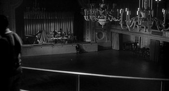 Movie still from “Love with the Proper Stranger” (1963), directed by Robert Mulligan – A black and white photo of a stage with a man sitting on the floor; Extreme Wide shot, High angle