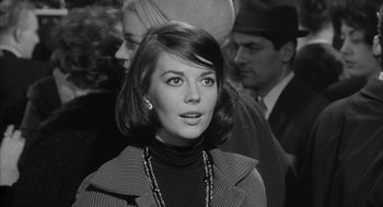 Movie still from “Love with the Proper Stranger” (1963), directed by Robert Mulligan – A black - and - white photo of a young woman in a crowd of people; Close Up shot, Over the shoulder angle