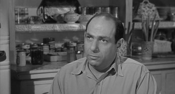Movie still from “Love with the Proper Stranger” (1963), directed by Robert Mulligan – A black and white photo of a man in a kitchen; Close Up shot, Over the shoulder angle