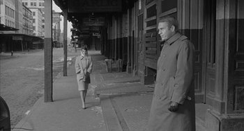 Movie still from “Love with the Proper Stranger” (1963), directed by Robert Mulligan – An old photo of a man and a woman on the sidewalk; Wide shot, Over the shoulder angle