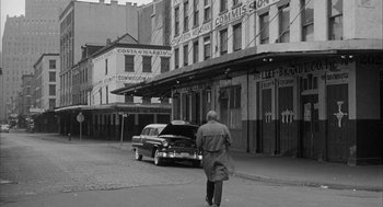 Movie still from “Love with the Proper Stranger” (1963), directed by Robert Mulligan – An older man walking down the street in front of an old car; Wide shot, Low angle