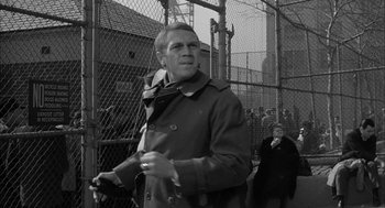 Movie still from “Love with the Proper Stranger” (1963), directed by Robert Mulligan – Black and white photograph of a man in a trench coat; Medium shot, Low angle