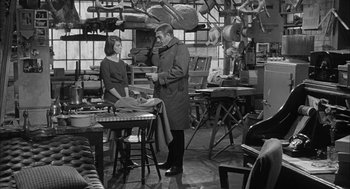 Movie still from “Love with the Proper Stranger” (1963), directed by Robert Mulligan – A man and a woman standing in front of a table; Medium shot, Over the shoulder angle