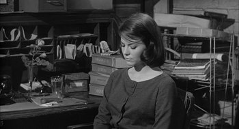 Movie still from “Love with the Proper Stranger” (1963), directed by Robert Mulligan – A woman sitting in front of a stack of books; Medium shot, High angle