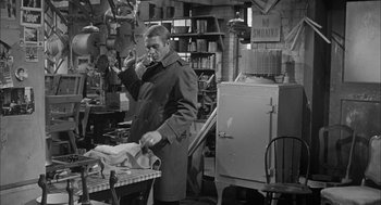 Movie still from “Love with the Proper Stranger” (1963), directed by Robert Mulligan – A black and white photo of a man standing in a room; Medium shot, Over the shoulder angle