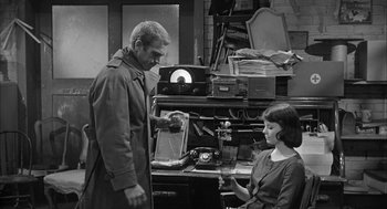 Movie still from “Love with the Proper Stranger” (1963), directed by Robert Mulligan – A man and a woman looking at each other in front of a desk; Medium shot, Over the shoulder angle
