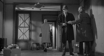 Movie still from “Love with the Proper Stranger” (1963), directed by Robert Mulligan – A man in a hat and a trench coat shaking hands with another man in a hat; Wide shot, Over the shoulder angle