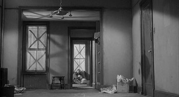 Movie still from “Love with the Proper Stranger” (1963), directed by Robert Mulligan – A person sitting in a room with a bag of groceries; Wide shot, High angle