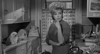 Movie still from “Love with the Proper Stranger” (1963), directed by Robert Mulligan – A black and white photo of a woman in a kitchen; Medium shot, Over the shoulder angle