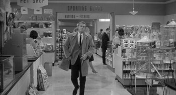 Movie still from “Love with the Proper Stranger” (1963), directed by Robert Mulligan – A black and white photo of a man walking in a department store; Wide shot, Over the shoulder angle