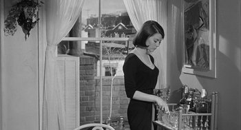 Movie still from “Love with the Proper Stranger” (1963), directed by Robert Mulligan – A black and white photo of a woman standing in front of a window; Medium shot, Low angle