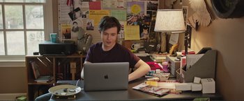 Movie still from “Love, Simon” (2018), directed by Greg Berlanti – A man sitting in front of an open laptop computer; Medium shot, High angle