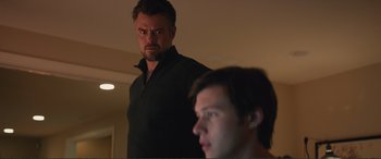 Movie still from “Love, Simon” (2018), directed by Greg Berlanti – A man standing next to another man in a dark room; Medium shot, Over the shoulder angle