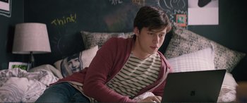 Movie still from “Love, Simon” (2018), directed by Greg Berlanti – A man sitting on the ground looking at a laptop computer; Medium shot, Over the shoulder angle