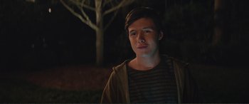 Movie still from “Love, Simon” (2018), directed by Greg Berlanti – A young man standing in front of a tree at night; Close Up shot, Over the shoulder angle