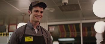 Movie still from “Love, Simon” (2018), directed by Greg Berlanti – A man wearing an apron and a hat smiles for the camera; Close Up shot, Over the shoulder angle